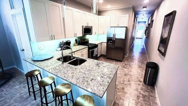 A kitchen with a granite countertop, stainless steel appliances, and a bar area with stools. - Greystone, 3500 sq ft, Rooftop Access, Sleeps 16 (Chicago)