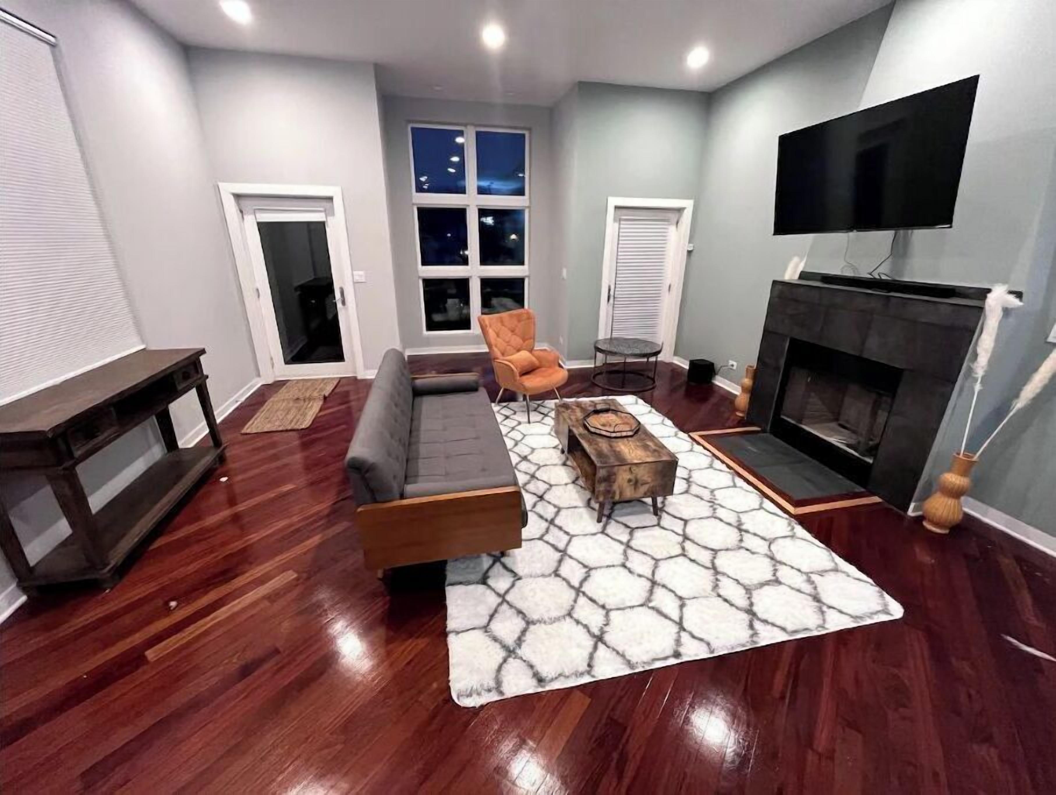 A living room with a sofa, a coffee table, a fireplace, and a TV mounted on the wall.
