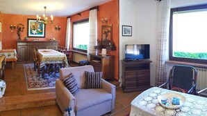 A cozy living room with a sofa, TV, dining area, and kitchen.