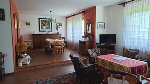 A dining area with a table and chairs, a television, and a window with curtains.