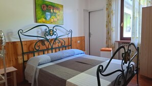 A bedroom with a metal bed frame, a wooden headboard, a striped bedspread, and a single bedside table.