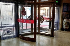 Une porte tournante avec une enseigne rouge, un vase décoratif et un sol carrelé.