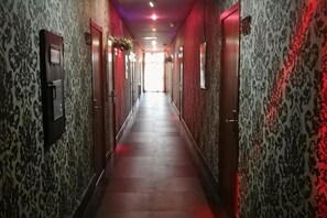 A hallway with patterned walls and doors, leading to a bright end.