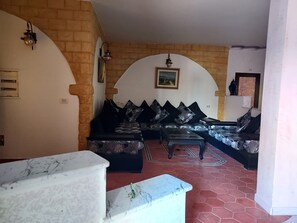 Una sala de estar con un juego de sofá, una mesita de centro y una mesa de mármol en primer plano.