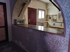 Una cocina con microondas, puerta de madera y utensilios colgando.