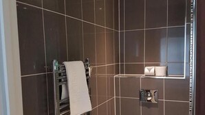 A modern bathroom with dark tiles, a white toilet, and a towel rack.