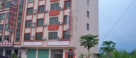 Un edificio de varios pisos con fachada plana, ventanas grandes y entrada verde.