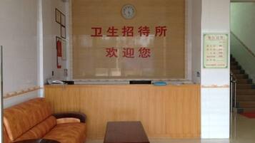 A reception area with a wooden reception desk, a clock, and a sign with text.