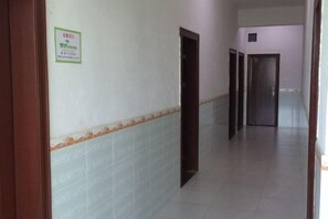 A hallway with tiled walls and a tiled floor, leading to a set of doors. - Weisheng Hostel (Xinfeng)