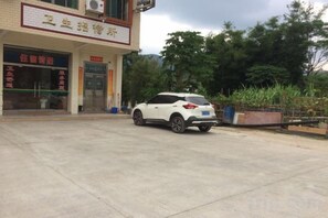 A building with a sign that reads 'Hotel' and a white car parked in front. - Weisheng Hostel (Xinfeng)