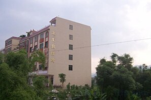 A multi-story building with a beige facade and a visible sign with Chinese characters. - Weisheng Hostel (Xinfeng)