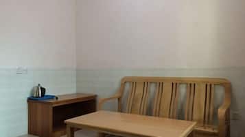 A room with a wooden chair and a small table, a blue tray with a kettle, and a wooden cabinet.