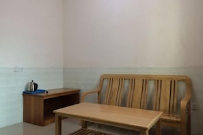 A room with a wooden chair and a small table, a blue tray with a kettle, and a wooden cabinet. - Weisheng Hostel (Xinfeng)