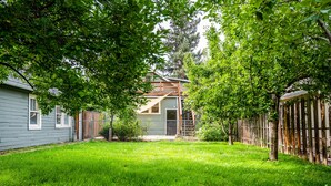 A residential backyard with a house, a fenced area, and a lawn.