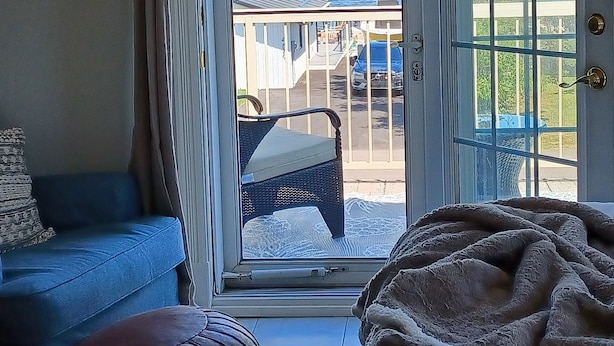 Ett rum med en skjutdörr i glas som leder ut till en balkong med utsikt över en vattenyta och en byggnad.