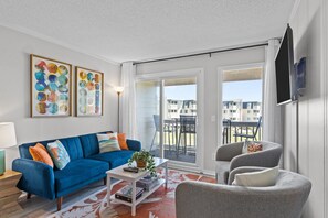 Relax in this stylish living room with a sofa, armchair, and flat-screen TV, plus a balcony with a view.