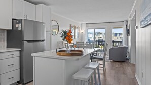Une cuisine moderne avec des meubles blancs, un réfrigérateur en acier inoxydable et un îlot central en bois agrémenté d’un vase de fleurs.