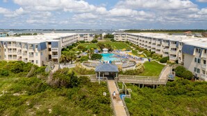Un complexe hôtelier comprenant plusieurs bâtiments, un espace piscine central et une promenade qui mène à la piscine.