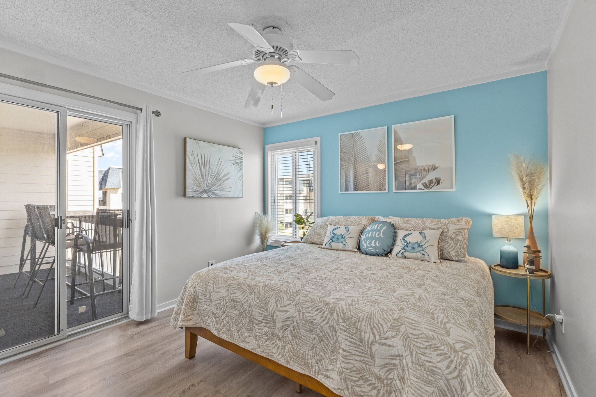 A bedroom with a bed, ceiling fan, and artwork on the walls.