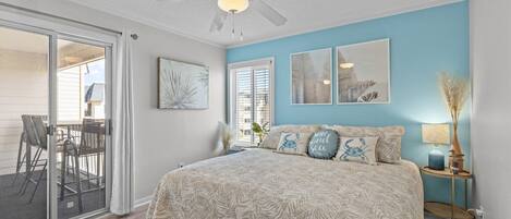 A bedroom with a bed, ceiling fan, and artwork on the walls.
