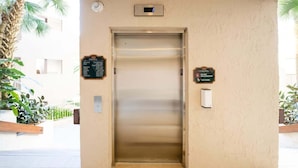 An elevator with a directory sign on the wall, a digital display above it, and a plaque to the right. - Sandcastle Court 219 (Nassau County)