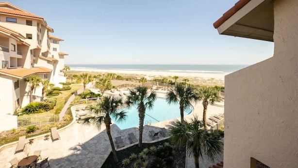 A resort with a pool, palm trees, and a view of the beach. - Sandcastle Court 219 (Nassau County)