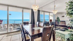 Een eetruimte met een grote tafel en stoelen, een kroonluchter en uitzicht op de oceaan.