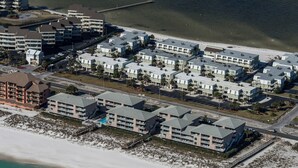 Luchtbeeld van een kusthotel met meerdere gebouwen, een strand en een pier.