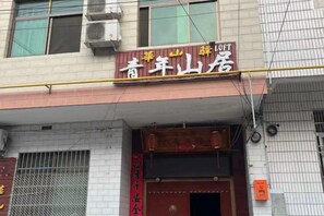 Un edificio con un cartel que dice 'Jiangnan Mountain Hotel' y una puerta de entrada roja.