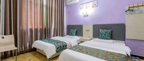 Habitación de hotel con dos camas, una silla, aire acondicionado y una lámpara fijada a la pared.
