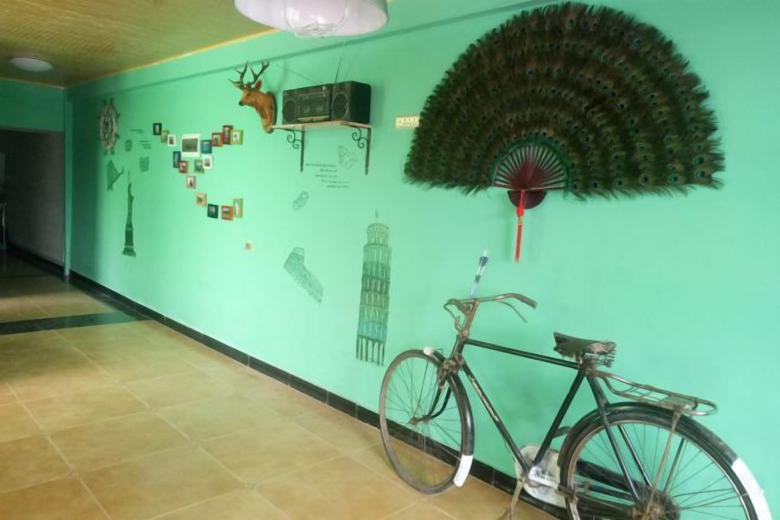 A hallway with a bicycle, wall decorations, and a fan.
