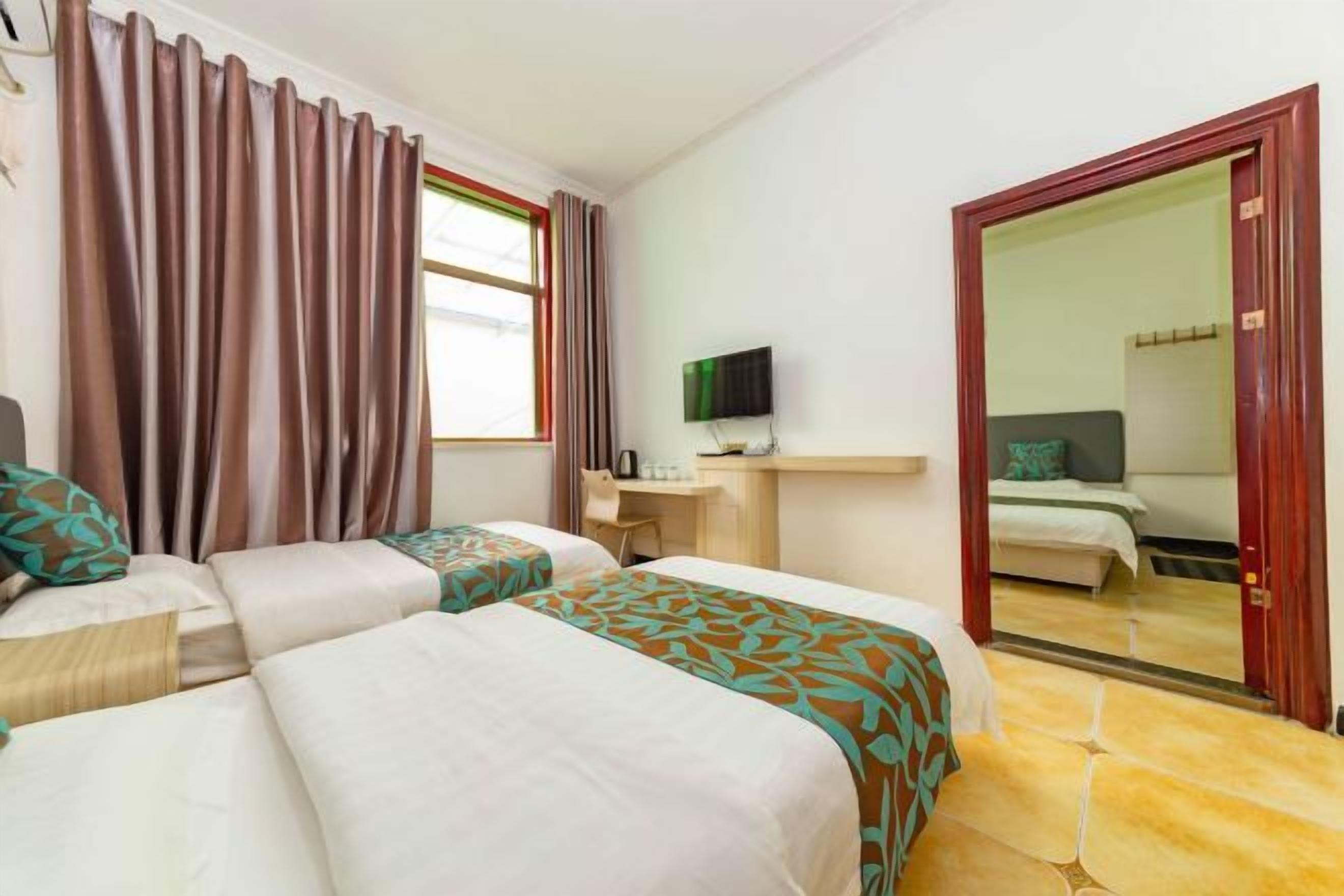 Een hotelkamer met twee bedden, een bureau met een televisie en een spiegel.
