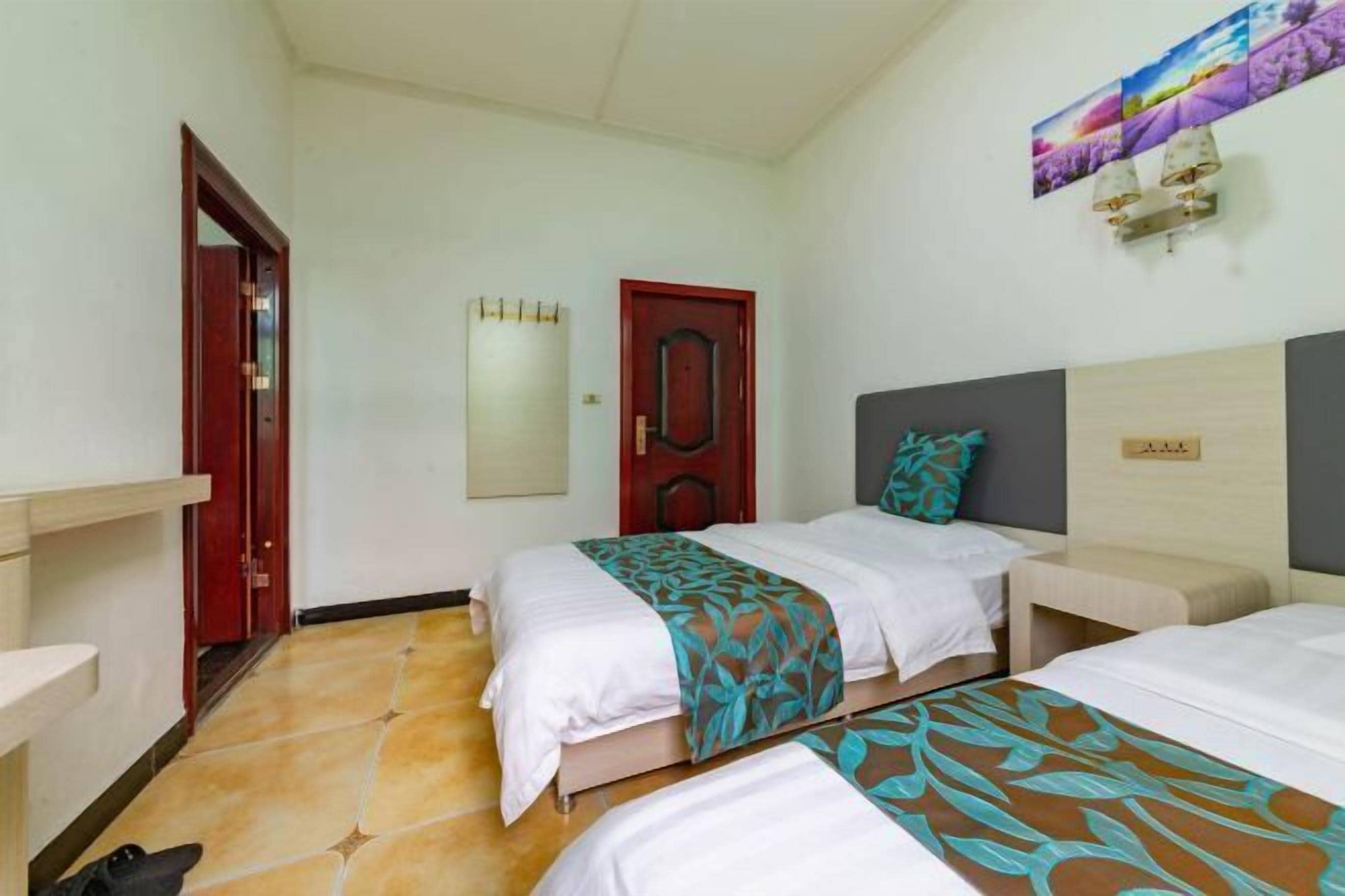 A hotel room with two beds, a wooden headboard, a red door, and a wall-mounted artwork.