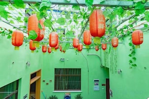 Una habitación con paredes verdes, un ventanal y faroles rojos colgantes.
