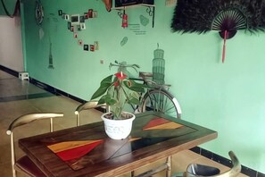Zona pranzo con tavolo in legno, sedie e una pianta in vaso.