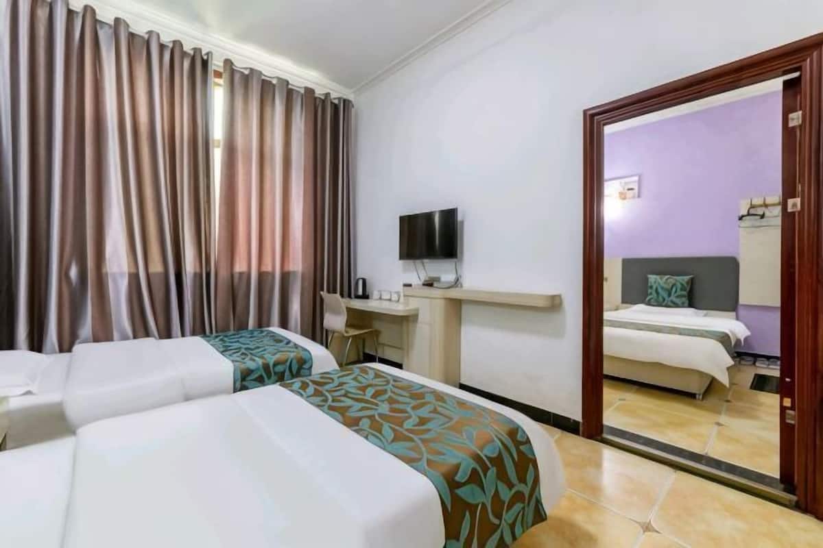 Een hotelkamer met twee bedden, een bureau, een televisie en een spiegel die de kamer weerkaatst.