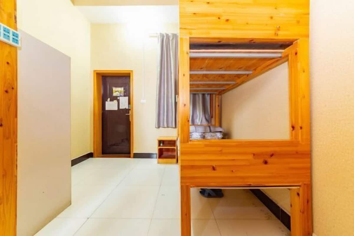 Een kamer met een stapelbed, een klein tafeltje en een deur met een bericht.
