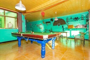 A pool table in a room with a green wall, a wooden ceiling, and a window with curtains. - Huashan - Loft Youth Mountain Residence (Huayin)