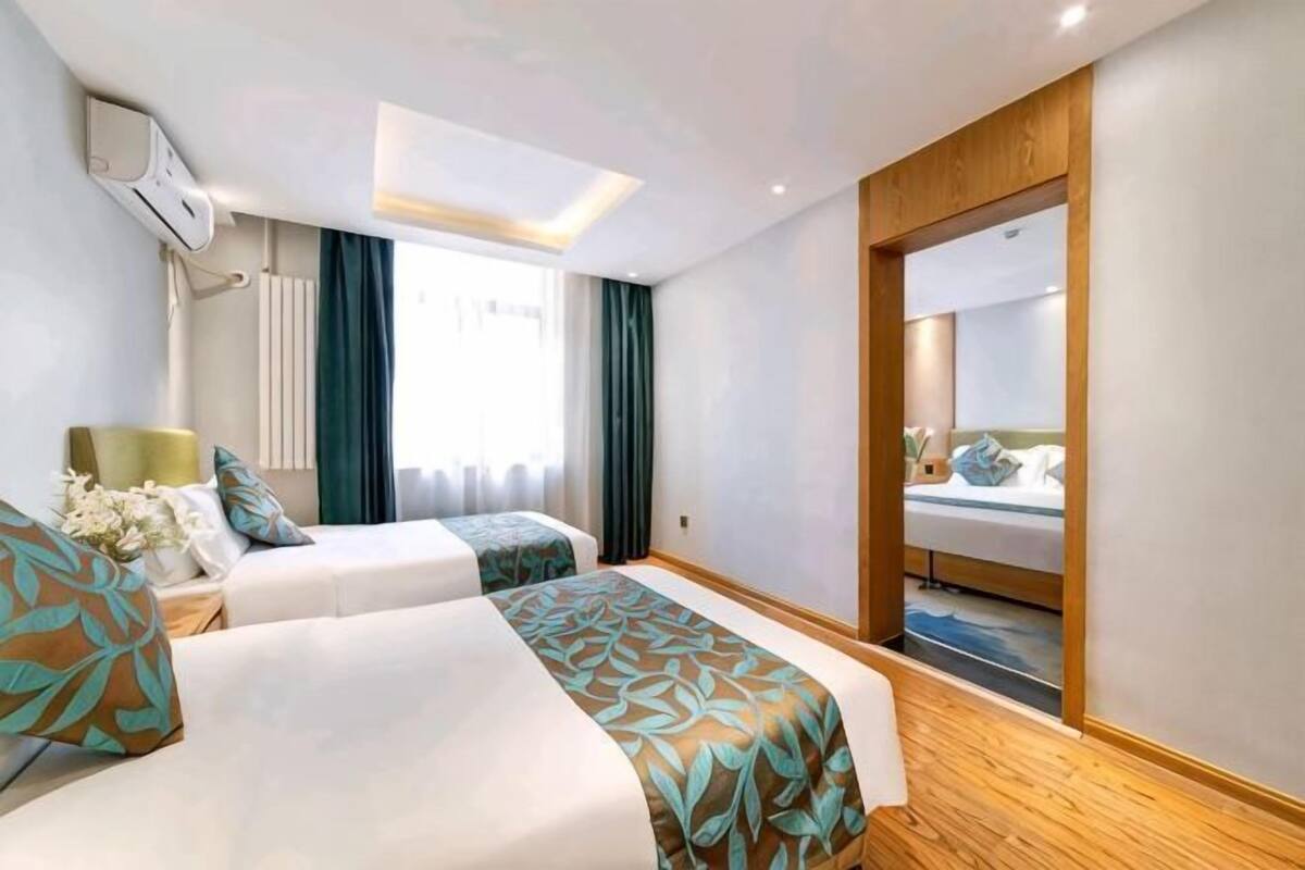 Een hotelkamer met twee bedden, een grote spiegel en een raam met gordijnen.