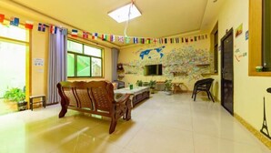 Una habitación con un sofá de madera, una mesa de comedor, un televisor y un mapa del mundo en la pared.