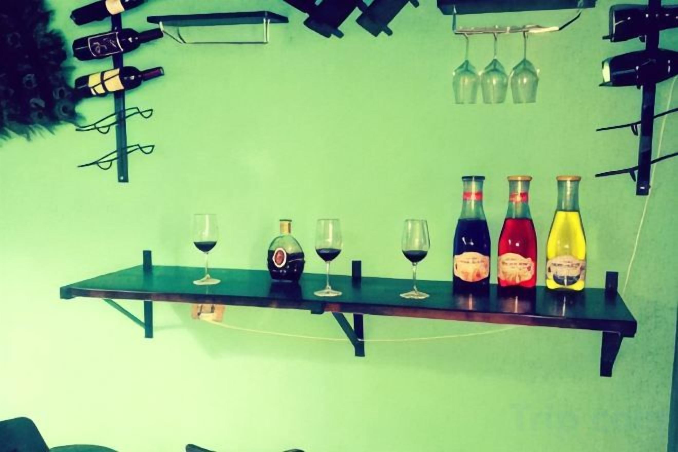 A bar area with a shelf holding bottles and glasses.