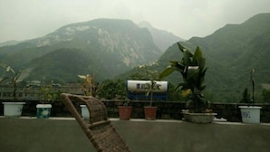 Un balcón con plantas en macetas y una silla, con vistas a un paisaje montañoso.