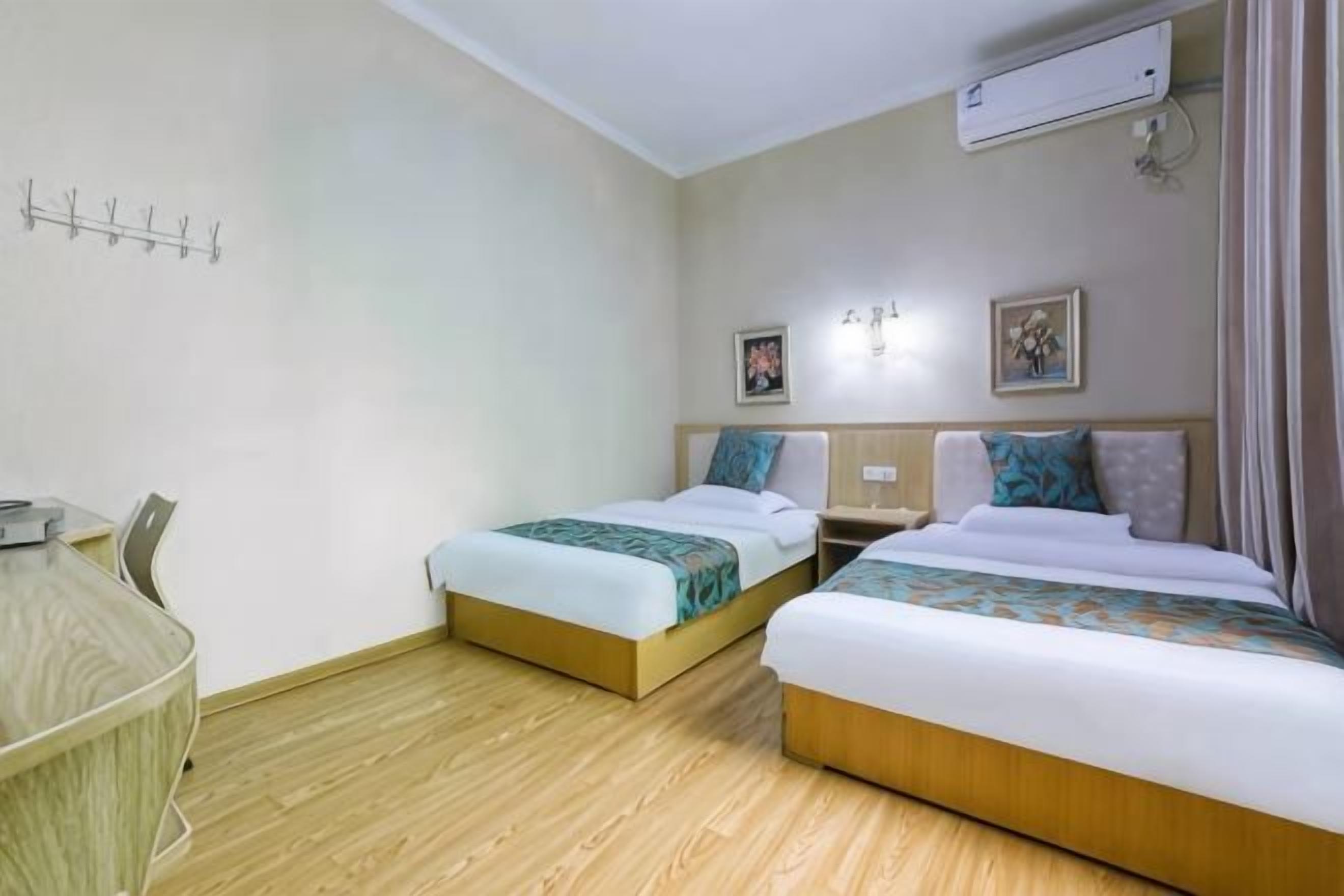 A hotel room with two beds, a desk, and a chair.