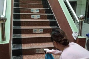 Una persona limpiando una escalera de mármol con un trapo.