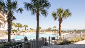 A private property with a swimming pool, palm trees, and a view of the ocean. - Sandcastle Court #220 -Kitchen (Nassau County)