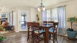 Un coin repas avec une table et des chaises en bois, un lustre et une plante en pot.