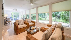 A spacious living area with wicker furniture, large windows, and a ceiling fan. - Fairway Oaks 3209 (Fernandina Beach)