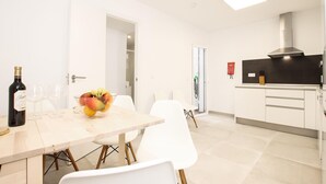 A modern kitchen with white cabinets, a black stove, and a dining area with a table and chairs. - GOLETA - Just 40 mts from the beach! (Port de Pollença)