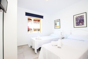 A hotel room with two beds, a window with a view of a building, and framed artwork on the walls. - GOLETA - Just 40 mts from the beach! (Port de Pollença)