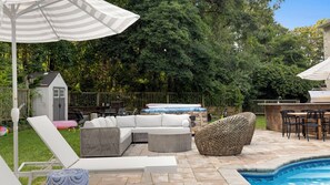 Un jardin avec une piscine, du mobilier d’extérieur et un espace barbecue.